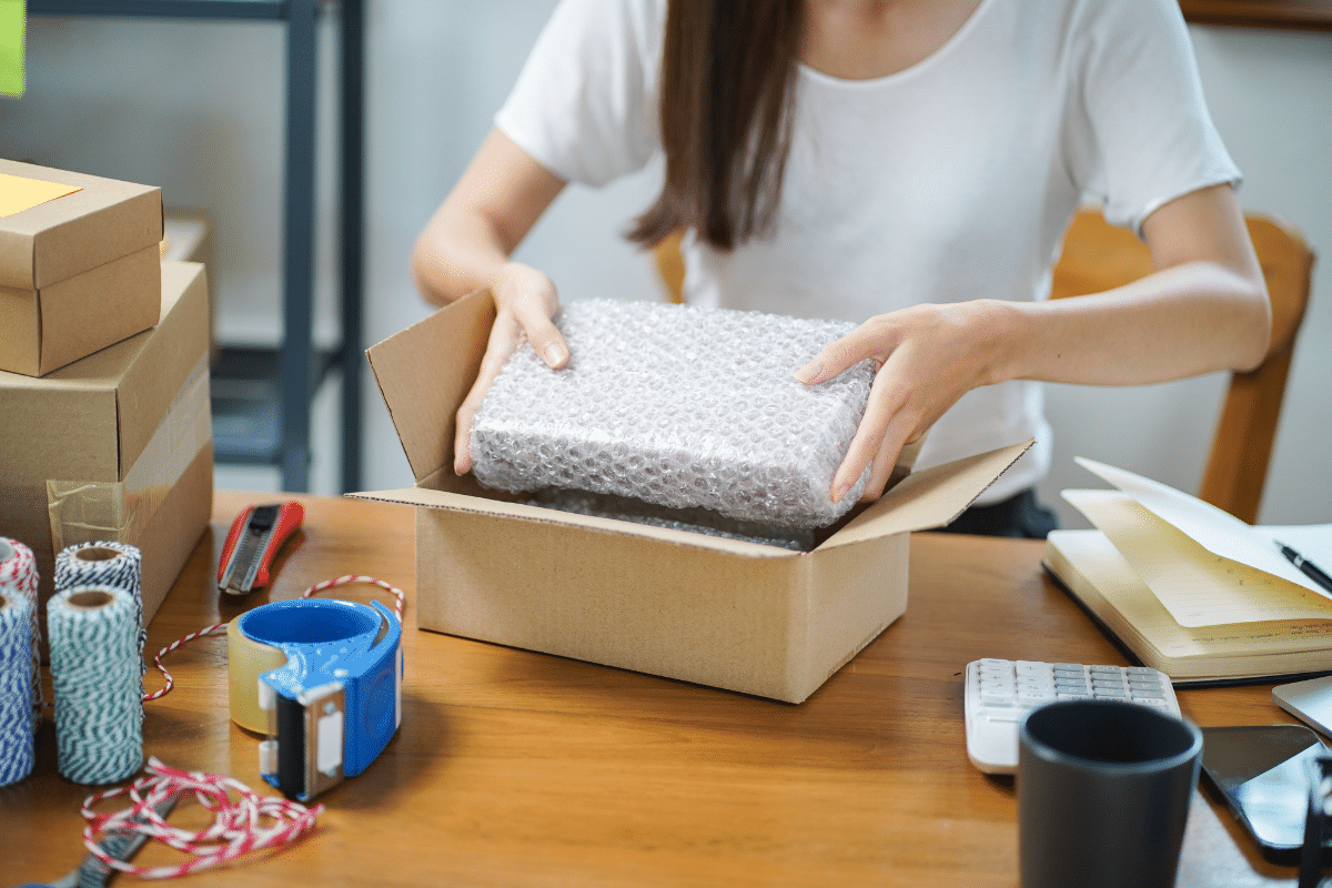 Person packing a parcel into a cardboard box before measuring it for dimensional weight
